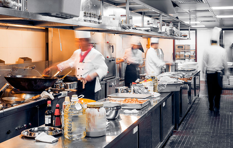 Großküche mit beschäftigten Köchen bei der Zubereitung von Speisen